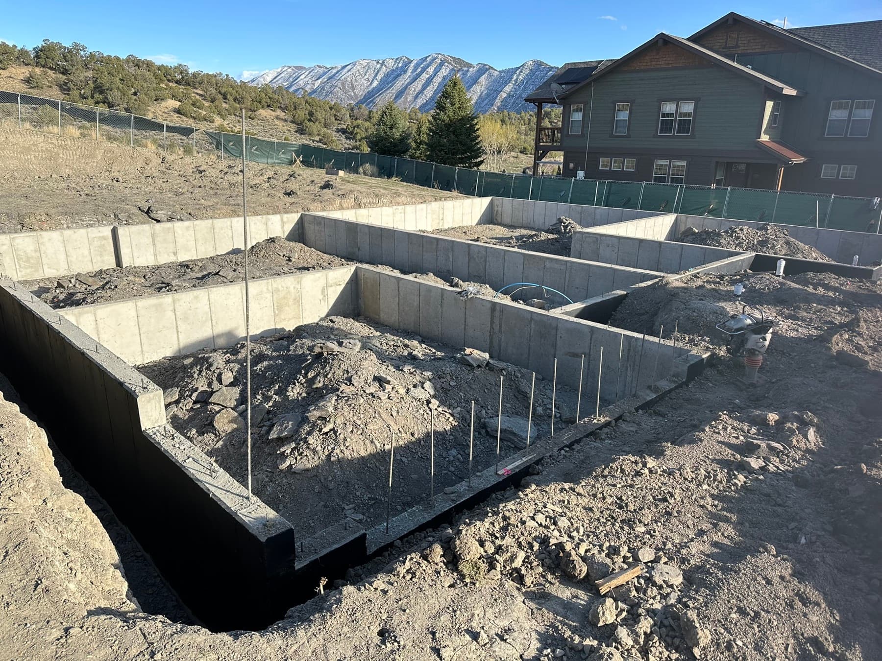 Poured concrete foundation walls with rebar, ready for framing, mountain backdrop