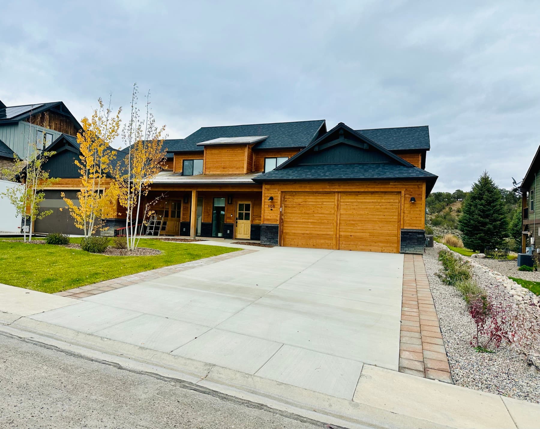 Completed custom home with concrete driveway, walkway, and landscaping — full-service general contracting